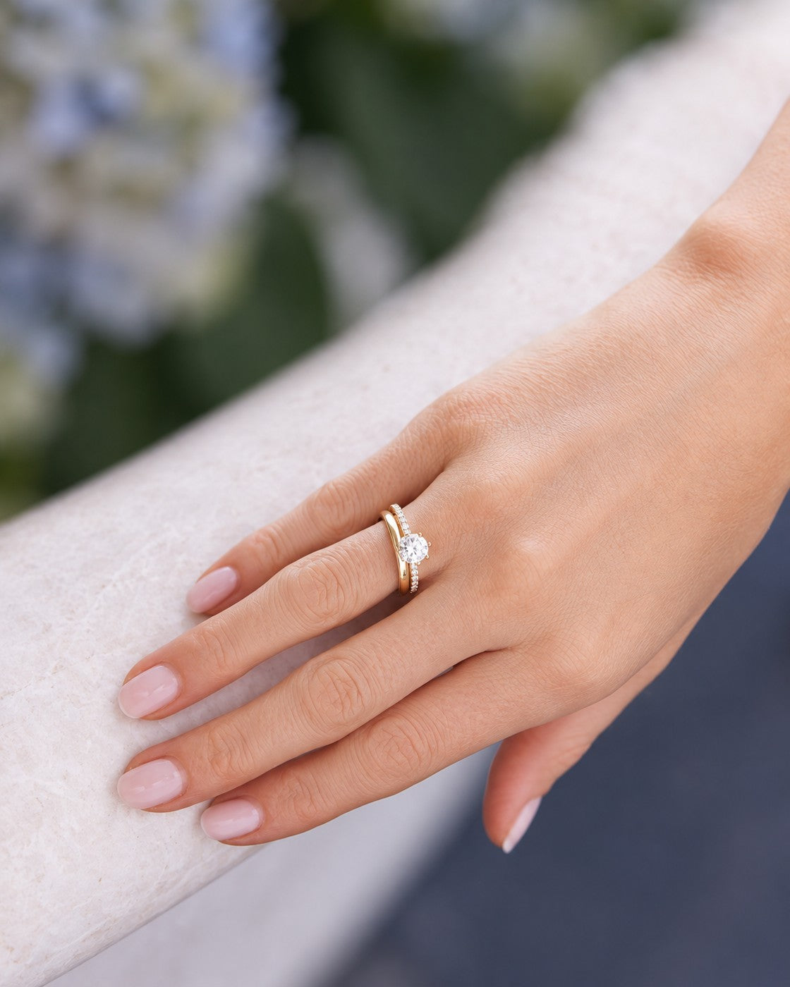 Nahaufnahme des GISELLE PROMISE Round Pavé Verlobungsrings mit CLASSIC Lady Ehering, getragen an einer Hand auf hellem Stein.